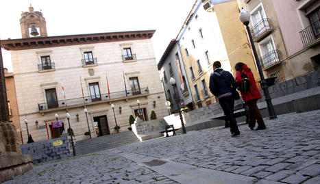Dos personas caminan por la Plaza Vieja de Tudela con el edificio del ayuntamiento, al fondo... NURIA G. LANDA