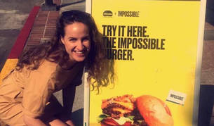 La pamplonesa In&eacute;s Resano, junto a un cartel anunciador de la hamburguesa sobre la que ella investiga.