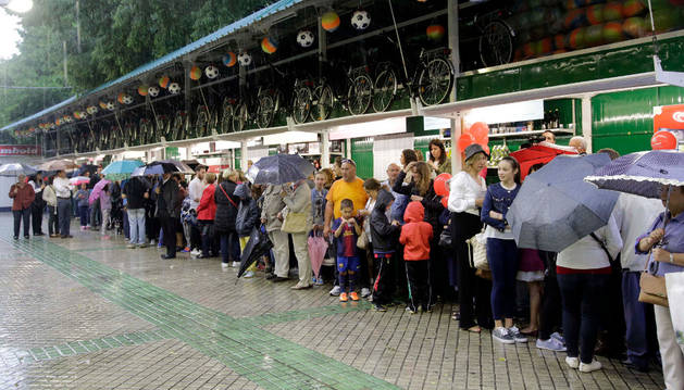 Los asistentes a la inauguración protegidos bajo paraguas y el tejadillo de la tómbola.