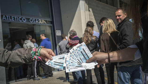 Unos aficionados muestran las localidades compradas ayer a primera hora de la tarde en las oficinas del estadio de El Sadar.