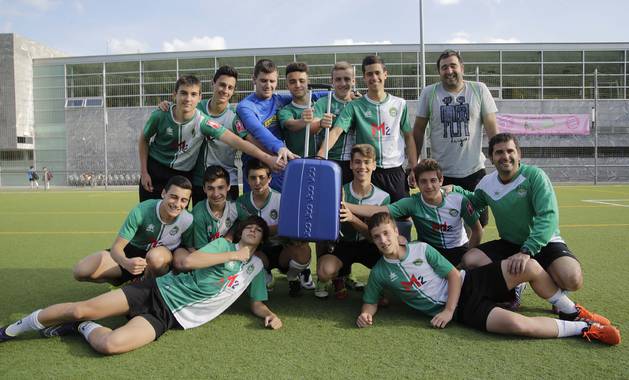 Los jugadores y entrenadores del Cadete A del Gazte Berriak posan junto a una maleta en el campo de fútbol de Ansoáin días antes de viajar a Málaga.
