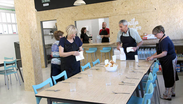 Los voluntarios preparan una de las mesas del comedor Villa Javier para el turno de comidas.