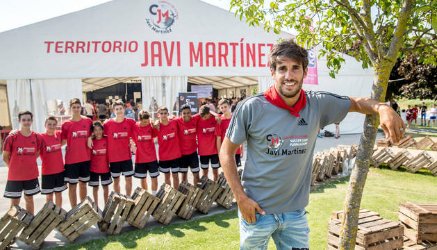 El jugador navarro del Bayern de Múnich, Javi Martínez, posa con el pañuelico de San Fermín delante de algunos niños que participan en su campus de verano en Ayegui.
