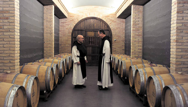 El hermano Daniel Gutiérrez Vesga (izda.) y el abad Isaac Totorika Izagirre (dcha.) en la bodega del monasterio rodeados por algunas de las barricas que se subastarán este viernes.