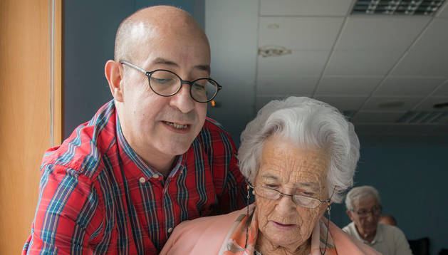 Miguel Lasaosa Zazo, voluntario de Cruz Roja, da cursos a mayores sobre el uso de teléfonos inteligentes. En la imagen, con una alumna.