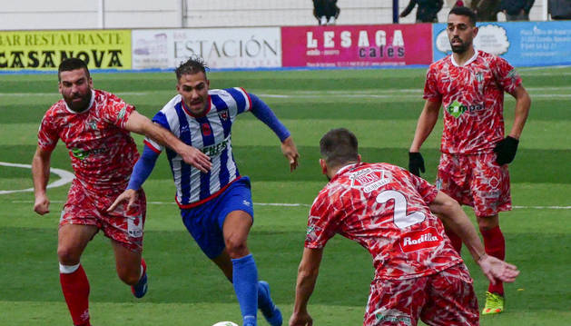 Yoel Sola, mediocentro del Izarra que se retiró ayer lesionado, conduce el balón rodeado por tres rivales del Guijuelo ayer.
