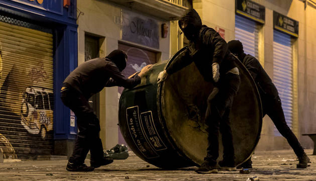 Imagen de tres encapuchados volcando un contenedor durante los incidentes registrados en la calle Chapitela.