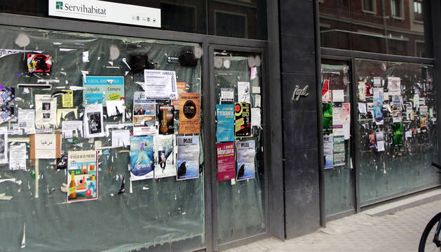Decenas de carteles publicitarios llenan el escaparate de un local comercial de la calle Bergamín.