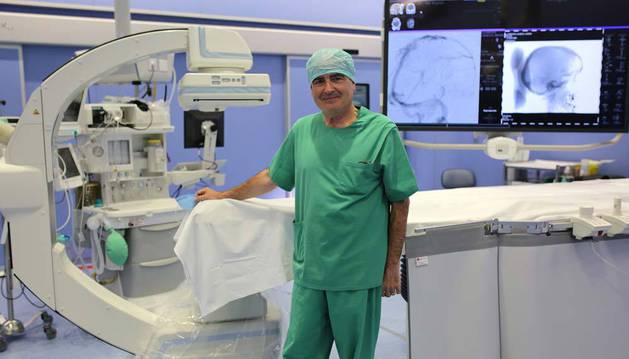 Imagen del doctor José Ignacio Bilbao posando en un quirófano híbrido de la Clinica Universidad de Navarra, junto a un equipo de radiología robotizado.