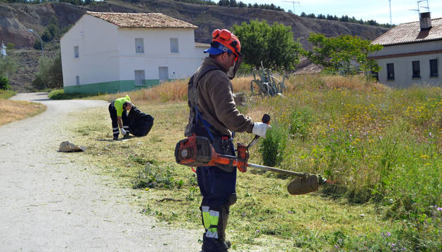 Imagen de trabajadores de la brigada medioambiental desbrozando unos terrenos frente al punto limpio.