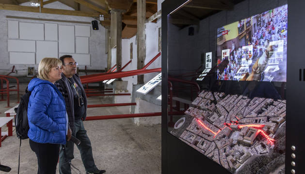 Una pareja contempla la maqueta del Casco Antiguo de Pamplona donde unas luces led iluminan el trazado del encierro.