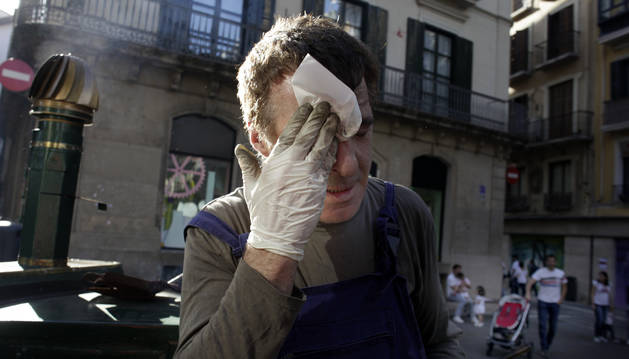 Harold, el castañero de la calle Mercaderes de Pamplona, se retira el sudor de la cara tras prender el carbón de la máquina.