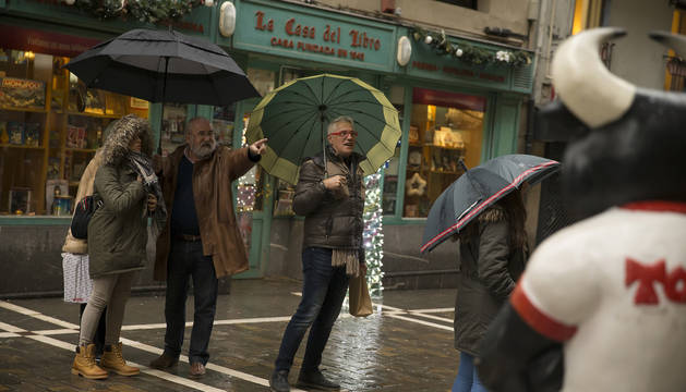 Un grupo de personas observan el escaparate de una de las tiendas de 'souvenirs' de la calle Estafeta.