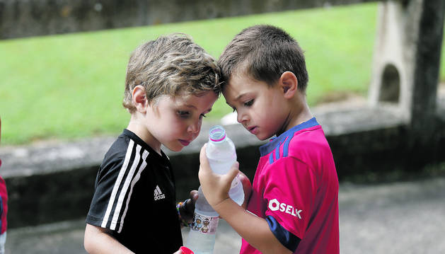 Dos jóvenes aficionados de Osasuna hidratándose en un día de pretemporada en Tajonar.
