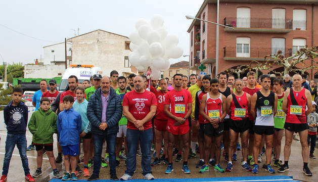 Los corredores junto con los alcaldes de Azagra y Andosilla guardando el minuto de silencio en la salida.