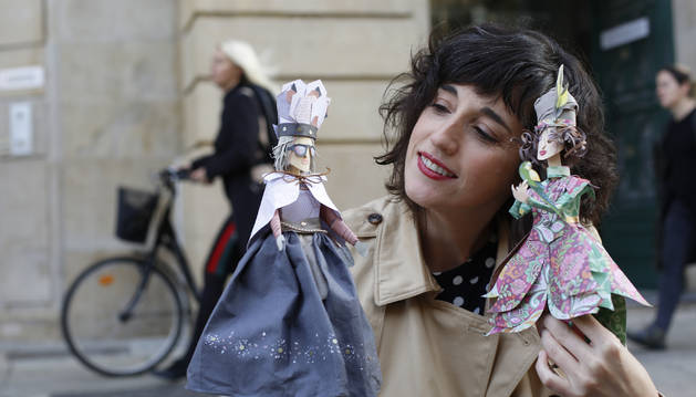 Mila García observa a su personaje futurista Paper World (izda) mientras sostiene a Paraíso (dcha) que sujeta un periquito.