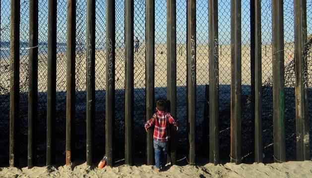 Un niño de la 'caravana migrante' se acerca al muro que separa México de Estados Unidos en Tijuana.