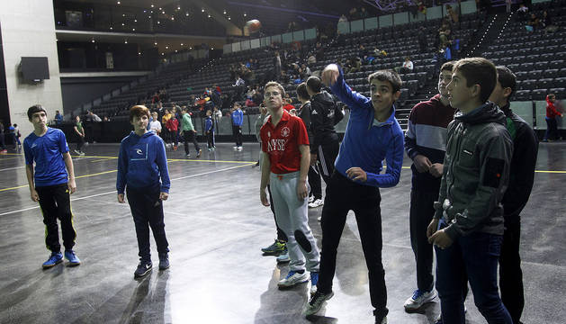 Un grupo de participantes observa a uno de ellos golpear la pelota en el frontón del Navarra Arena.