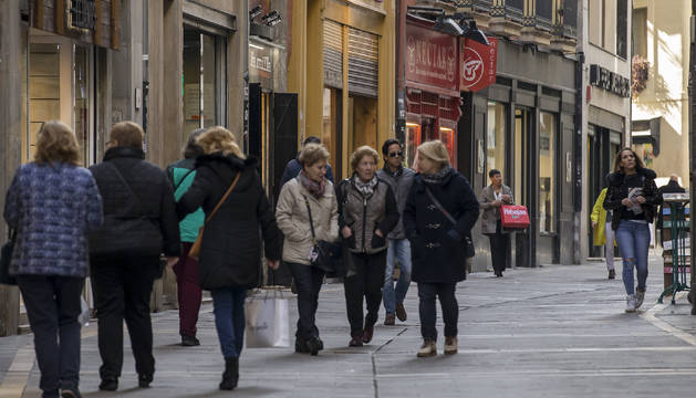 Varios grupos de personas pasean en la calle Zapatería, del Casco Viejo de Pamplona, con bolsas de compras.