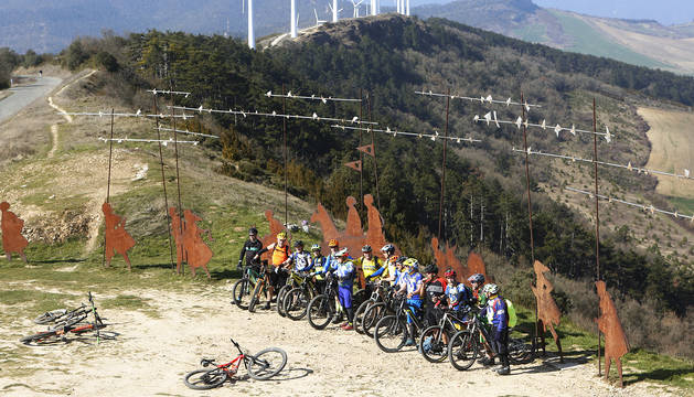Un grupo de ciclistas se fotografía junto al monumento al peregrino de El Perdón en una soleada jornada.