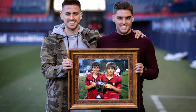 Kike Barja y Endika Irigoien posan en el estadio con una fotografía de ambos en verano del 2011, cuando ganaron en San Sebastián un torneo en categoría cadete.