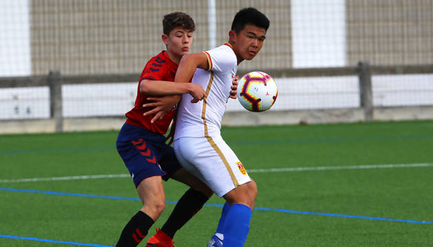 Un componente de la selección china sub-15 protege el esférico ante un jugador de las categorías inferiores de Osasuna.