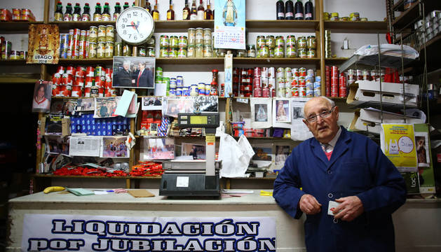Amalio López de Dicastillo Yániz, al otro lado del mostrador en el que trabaja desde 1956. En la mano, su carné de socio de Osasuna.