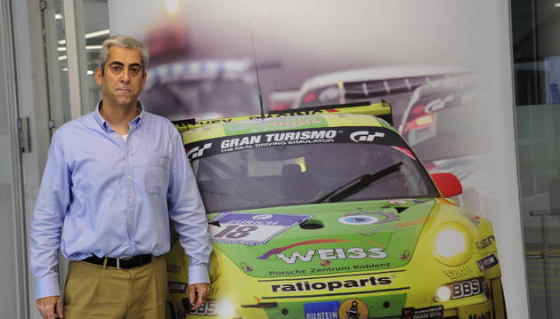 Foto de Guillermo Alonso, director de GKN Carcastillo, delante de una pared con la foto de un coche de carreras para quien fabrica transmisiones.