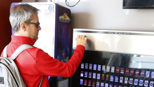 Una persona introduce un billete en una máquina expendedora de tabaco en un bar para sacar una cajetilla.
