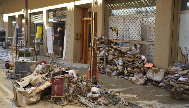 Basura, escombros, género dañado y persianas de negocios bajadas en la Calle Martínez de Espronceda, balance de las riadas del lunes en Tafalla.