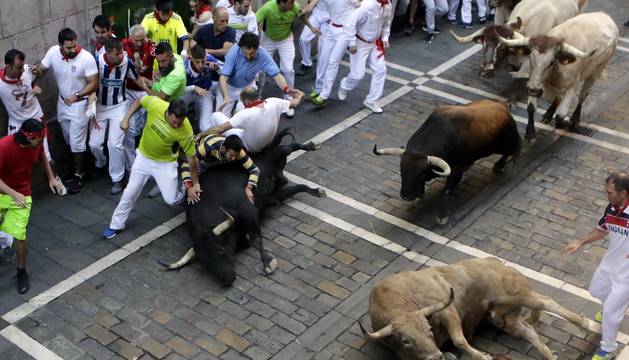 Momentos de tensión cuando el morlaco jabonero de la ganadería de Núñez del Cuvillo perdió pie en la calle Estafeta y cayó al suelo, rodeado de mozos.
