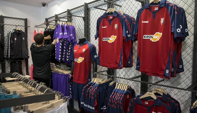 Foto de un cliente supervisando las camisetas de portero. A la derecha, la primera equipación expuesta en la tienda del club de El Sadar.