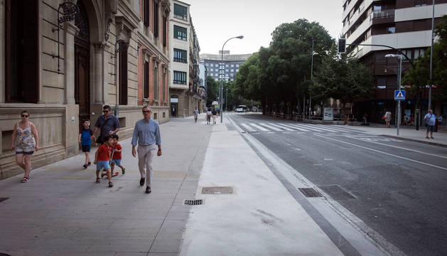 Foto de varias personas, por la acera enlosada del Parlamento de Navarra. A la derecha, la zona ampliada y rematada con hormigón.
