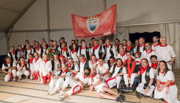 Foto de los integrantes de la peña La Teba, con chalecos negros, junto con Tudelanos Populares de otras ediciones y representantes de la entidad organizadora.