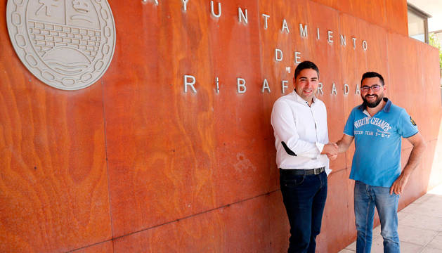 Tirso Calvo, a la izda., y Jesús Mª Rodríguez, estrechan sus manos ante la fachada del Ayuntamiento.