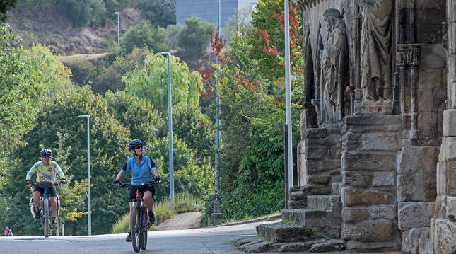Dos personas acceden en bicicleta al entorno de Curtidores y contemplan la iglesia del Santo Sepulcro.