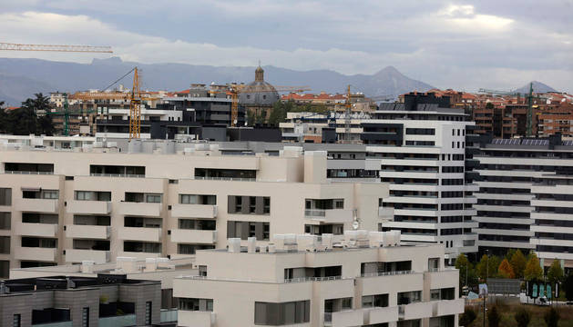 Foto, en primer plano, de viviendas del barrio pamplonés de Lezkairu; al fondo, el Ensanche.