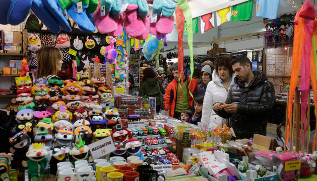 Foto de varios visitantes preguntando por los objetos expuestos en uno de los puestos de la Feria de Navidad.