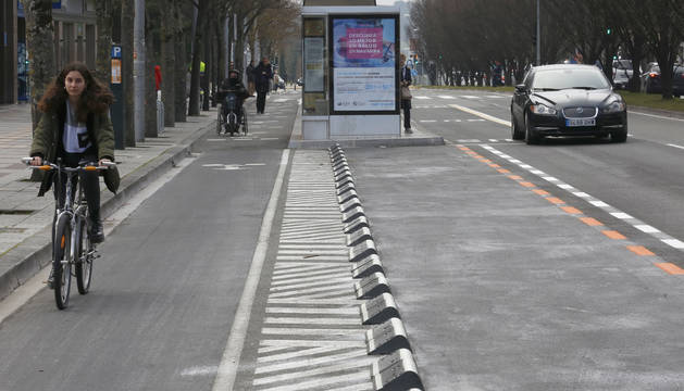 Una ciclista recorre el carril en Pío XII. En medio, el espacio convertido en zona naranja. A la derecha, un coche circula por la calzada.
