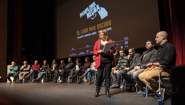Foto de Susana Rodríguez Lezaun, de pie, presentando a los autores. Desde la izquierda, Juan Carlos Berrio, Jon Alonso, Carlos Ollo, Jon Arretxe, Tadea Lizarbe, Yolanda Almeida, Javier Corpas Mauleón, Estela Chocarro, Maribel Medina, Maite Sota, Nuria Viedma (a la que tapa Rodríguez Lezaun), Miguel Izu, Aitor Iragi, Carlos Bassas, Luis Martínez Vallés y Carlos Erice.