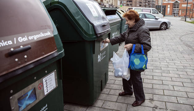 Una mujer acerca la tarjeta magnética para abrir el contenedor de materia orgánica, en Azpilagaña.
