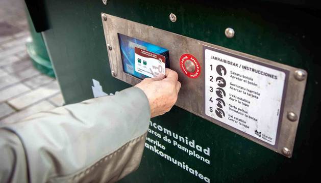 Un ciudadano acerca su tarjeta magnética al contenedor para abrirlo y depositar los residuos.