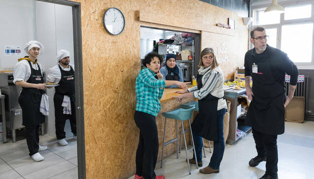 Varios voluntarios del comedor social Villa Javier Tudela se disponen a servir los platos a los usuarios.