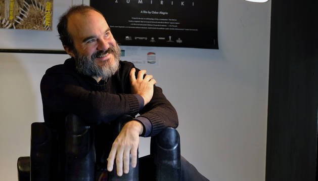 Foto de Oskar Alegria hace unos días en una cafetería de Pamplona. Al fondo, el póster de Zumiriki, con los árboles de la isla.