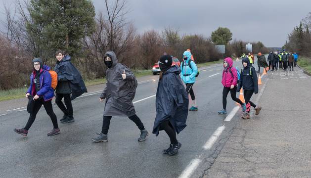 Foto de un grupo de peregrinos se protege con chubasqueros de la lluvia en la recta de Arguedas.