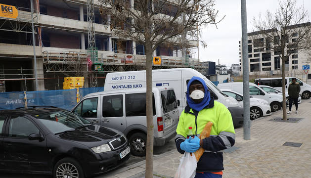 Un trabajador se protege con una mascarilla en una calle de Lezkairu con un edificio en construcción.