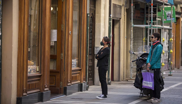 Foto de dos personas esperan a ser atendidas en una panadería del centro, respetando la distancia de seguridad.