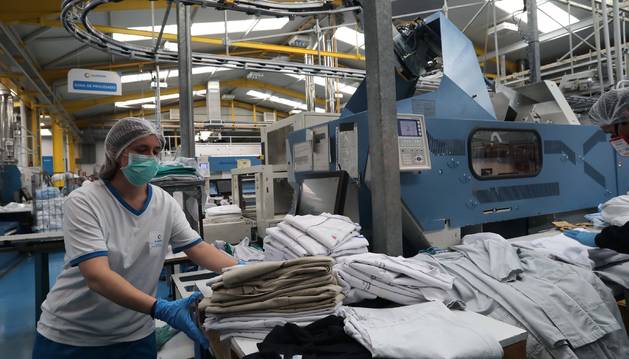 Foto de trabajadora, ordenando este jueves uniformes limpios de sanitarios en la planta de Noáin de Ilunion-Lavanor.