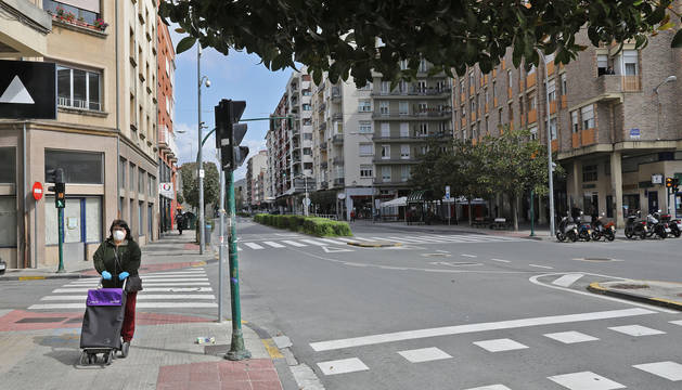 Una mujer con el carro de la compra y en solitario por la anteriormente concurrida calle Mayor de Burlada.