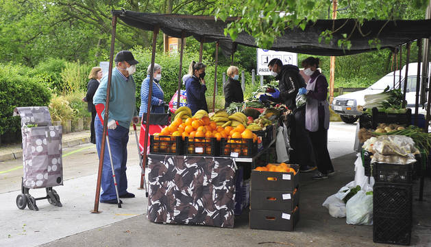 Varias personas cubiertas con mascarillas guardan la distancia de seguridad en el mercadillo de Peralta.